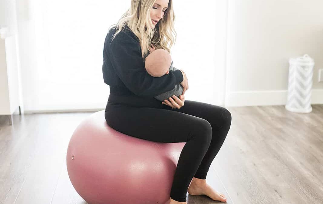 Mom sitting on a yoga ball holding her newborn
