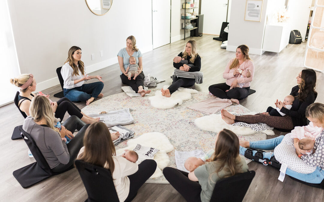 New moms sitting in a circle on the floor holding their babies