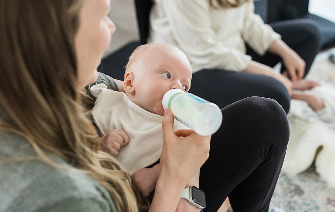 A new mom bottle feeding her newborn in her arms