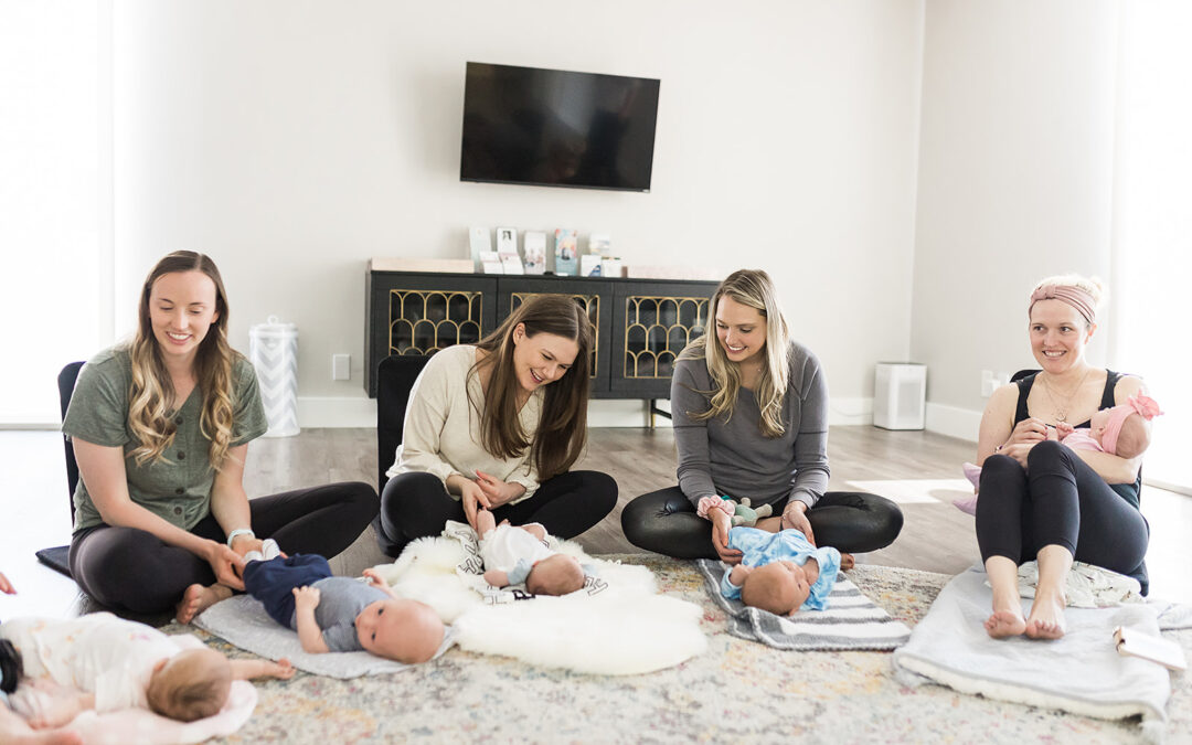 Moms sitting on the floor playing with their babies